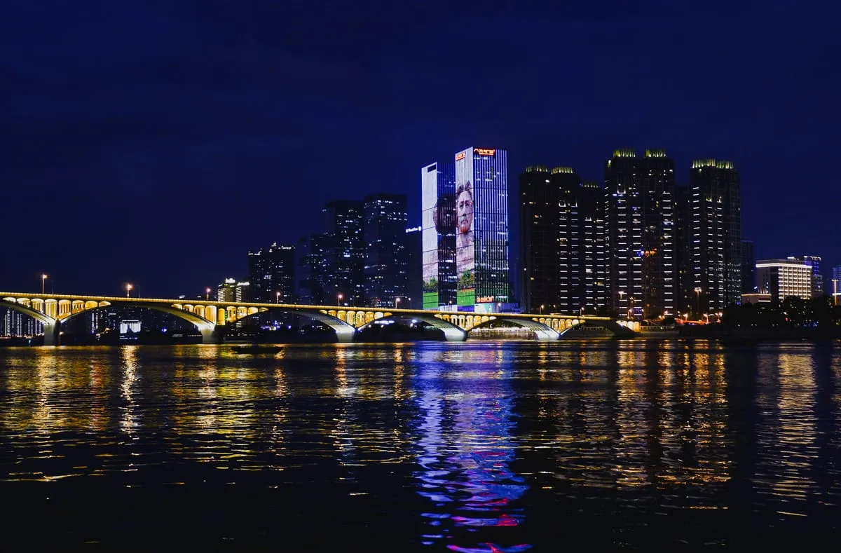 夜晚的城市天際線，橋樑燈光倒映在河面上。